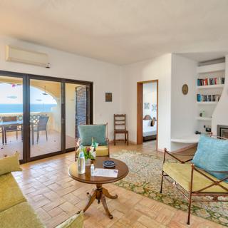 Algar Seco Parque | Carvoeiro, Algarve | t2 sala com sofas livros lareira terraco e vista mar